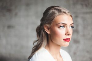 blue-eyed, blonde woman with smooth facial skin and red lipstick